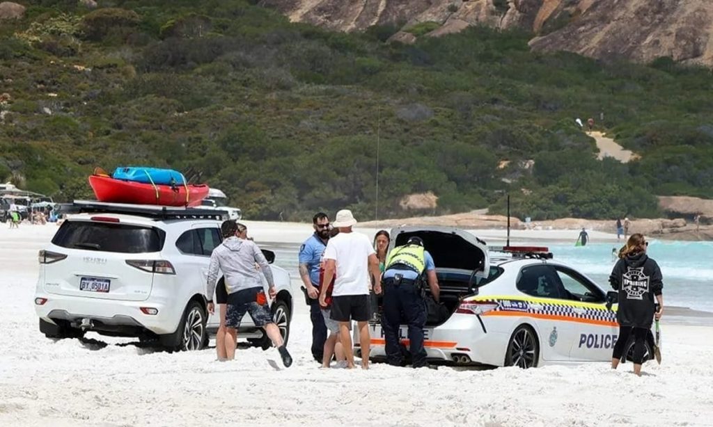 Carro de polícia fica atolado na areia e é resgatado por banhistas