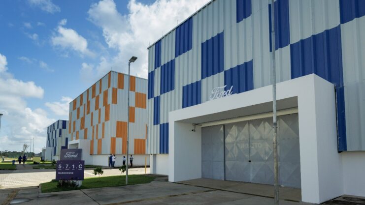 Fachada da sede do Centro de Desenvolvimento e Tecnologia da Ford Brasil com três blocos. Dois deles apresentam pintura quadriculada de azul com branco e um, de laranja com branco.