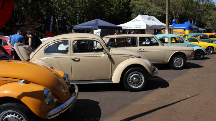 Modelos de carros antigos, incluindo fuscas laranja e bege, sendo expostos no California Volks Brothers.