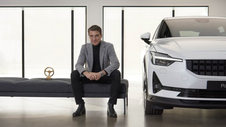 Thomas Ingenlath, CEO da Polestar, sentado ao lado de carro branco da marca