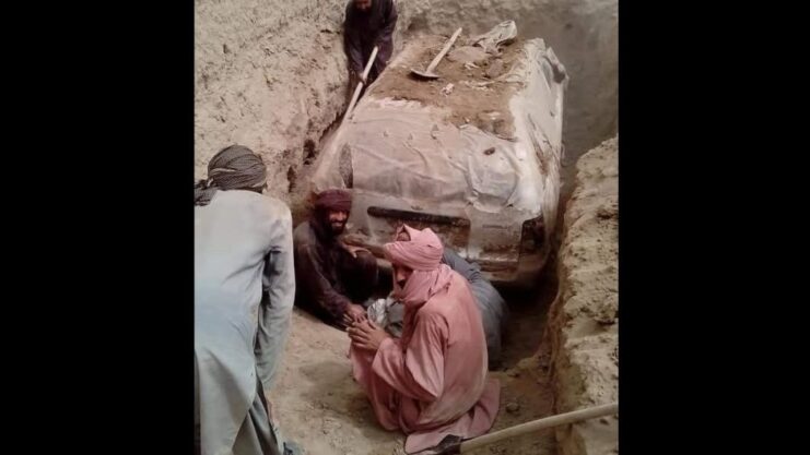 Pessoas trabalhando no desenterro do Toyota Corolla E100 no Afeganistão.