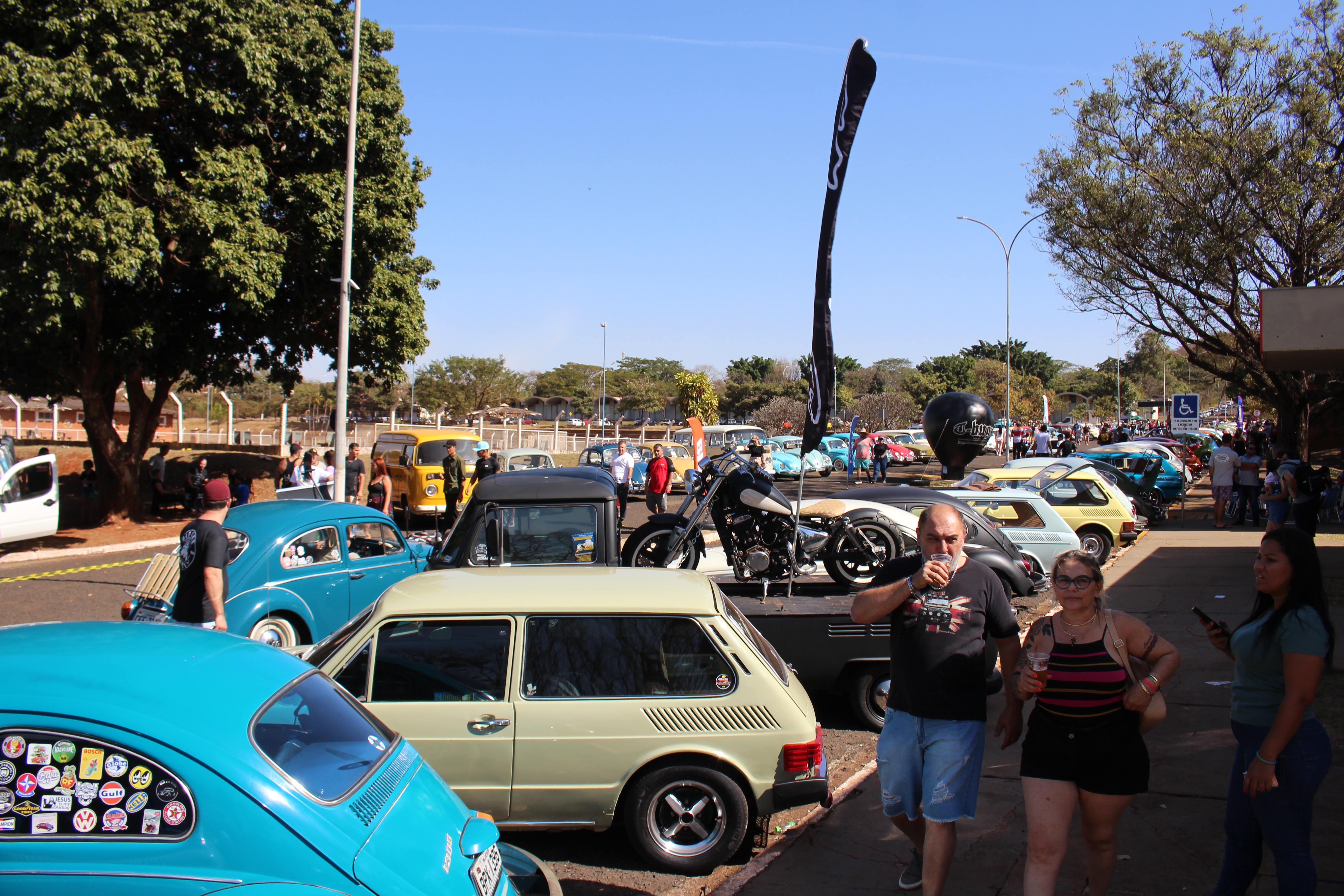 Modelos de carros antigos sendo expostos no California Volks Brothers com várias pessoas ao redor. 