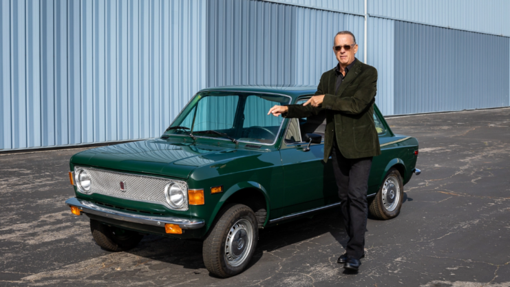 Tom Hanks posando com seu Fiat 128 na cor verde.