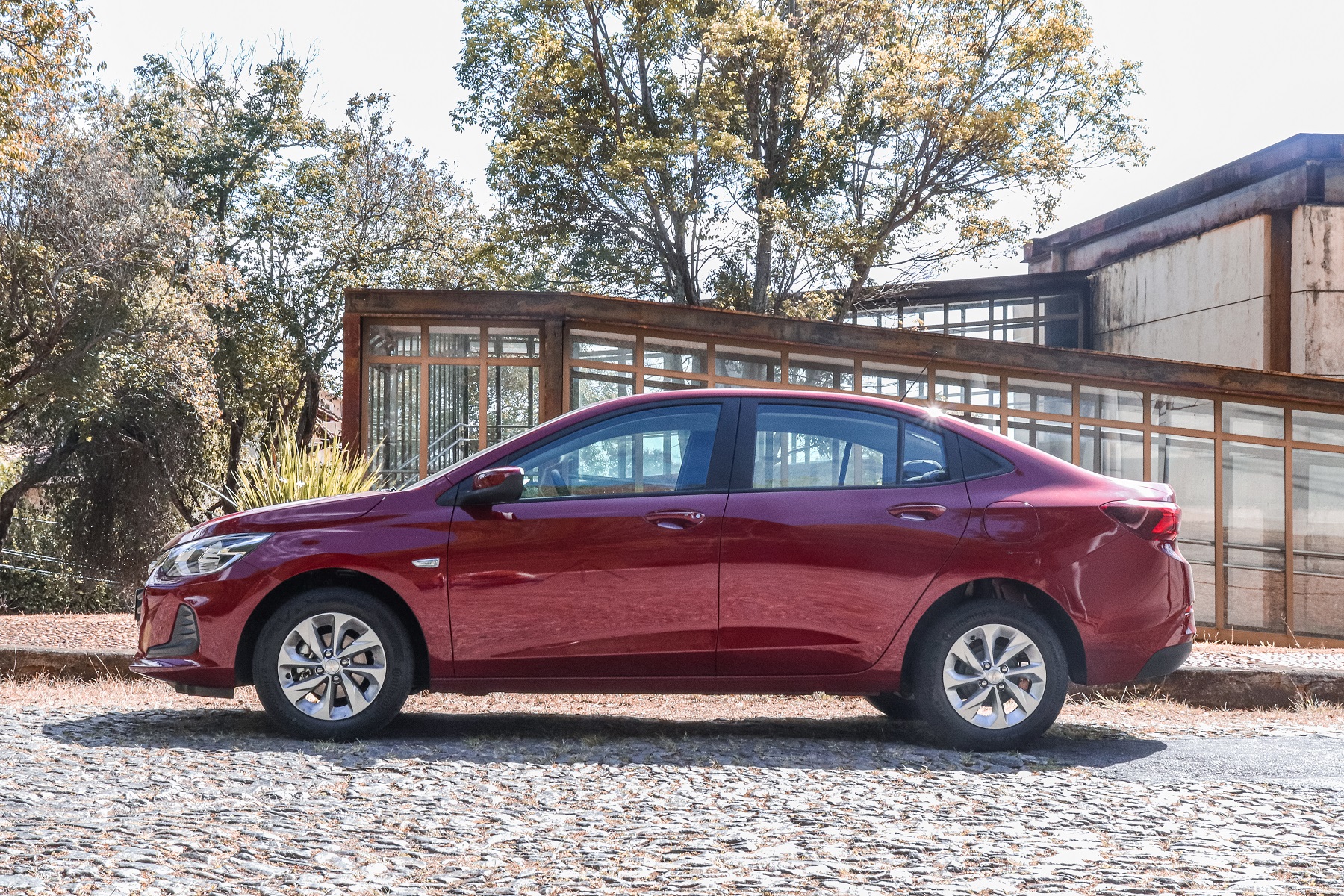 Chevrolet Onix Plus vermelho 2022 estacionado de lateral.