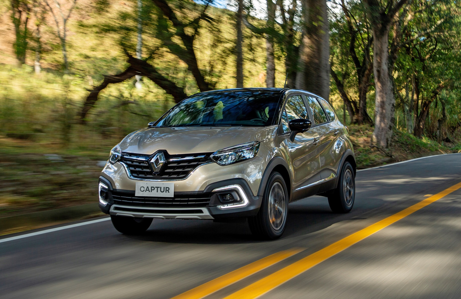 Renault Captur Iconic 2022 em movimento em estrada arborizada