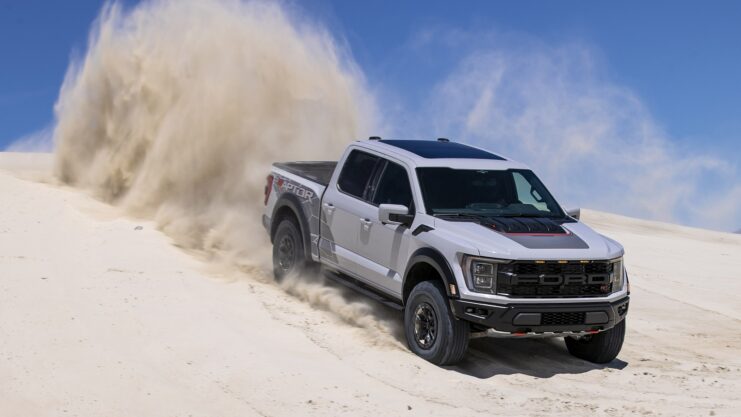 Ford F-150 Raptor cinza de frente descendo duna de areia
