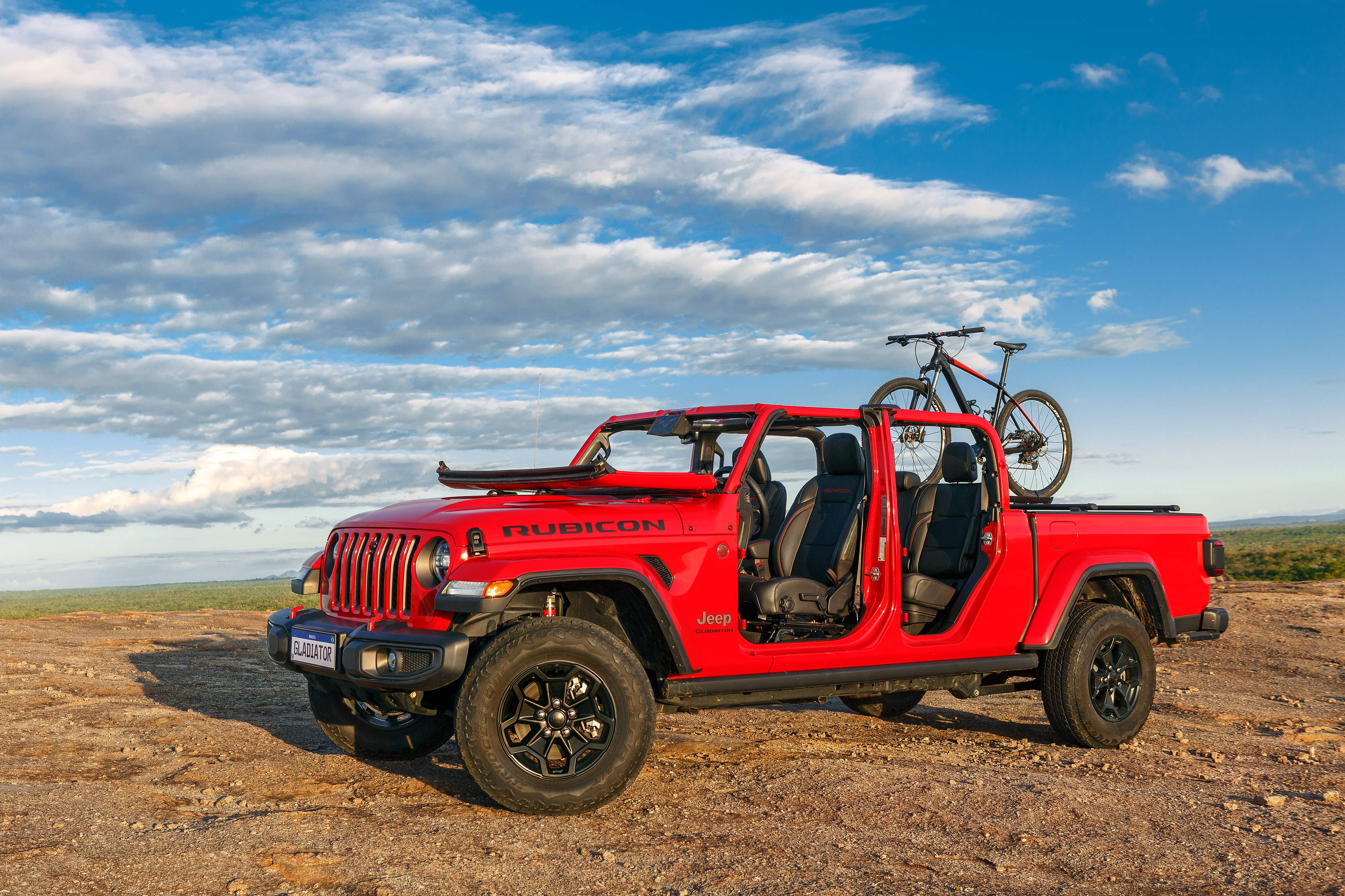 Jeep Gladiator Rubicon 2022 vermelho de frente desmontado com uma bicicleta na caçamba.