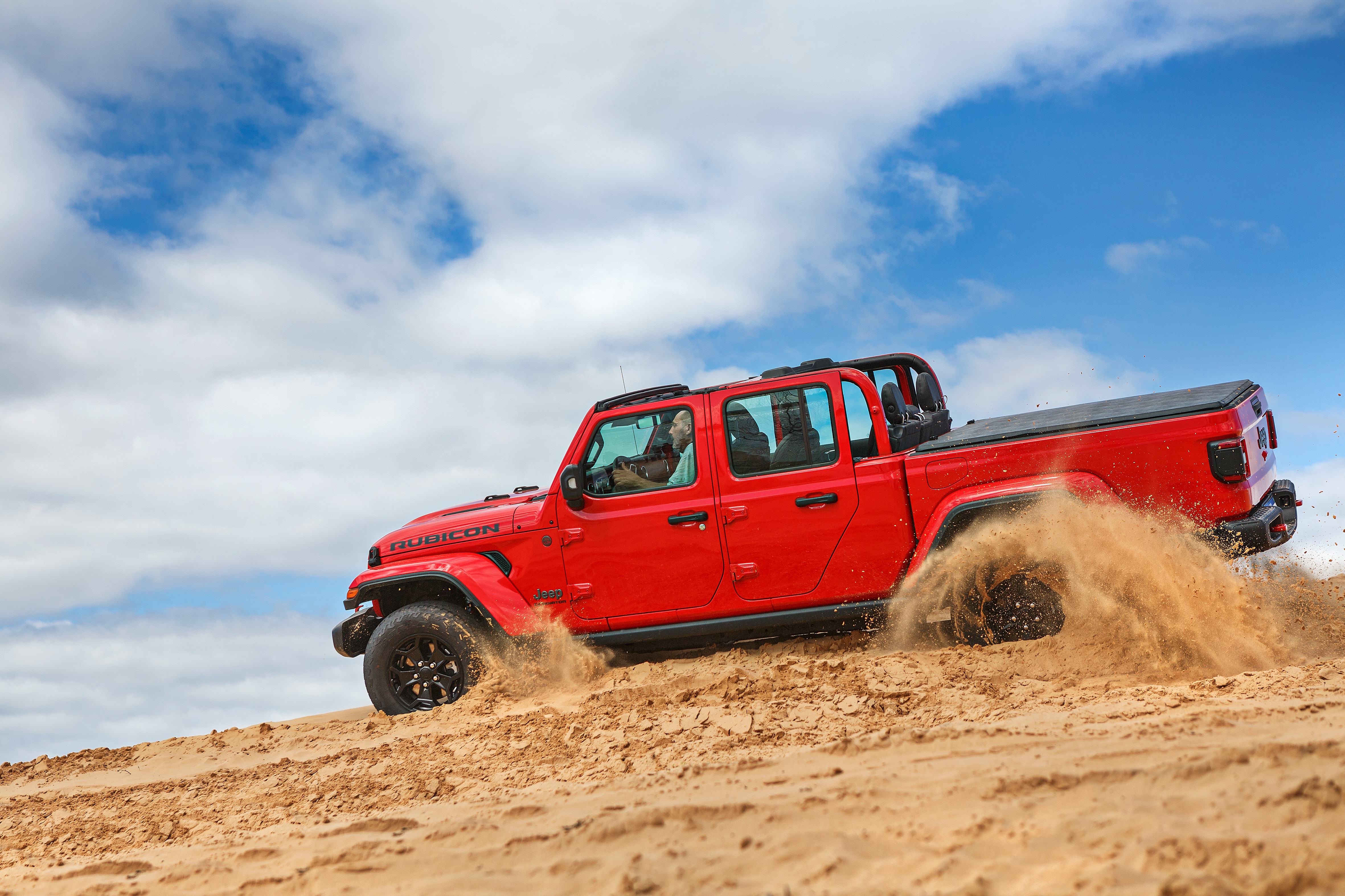 Jeep Gladiator Rubicon 2022 vermelho de lado rodando na areia.