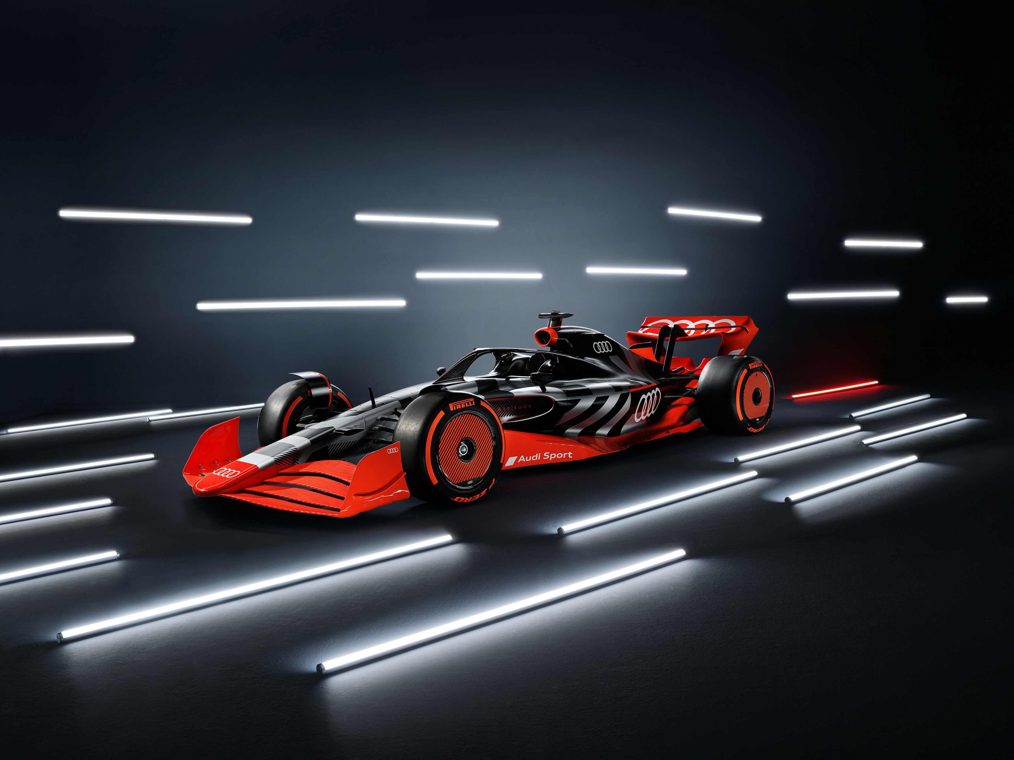 Imagem ilustrativa do carro-conceito vermelho da Audi para a Fórmula 1, visto da diagonal frontal, em estúdio com várias luzes ao seu redor; 
