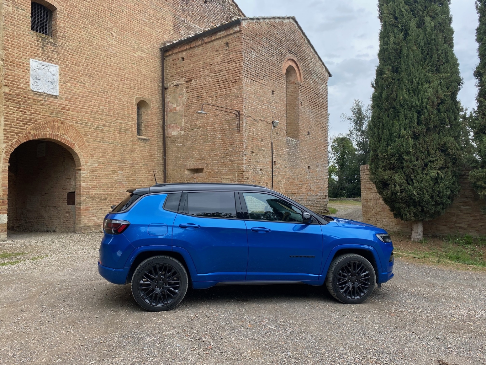 Jeep Compass 4xe híbrido plug-in azul de lateral na Toscana pista de terra