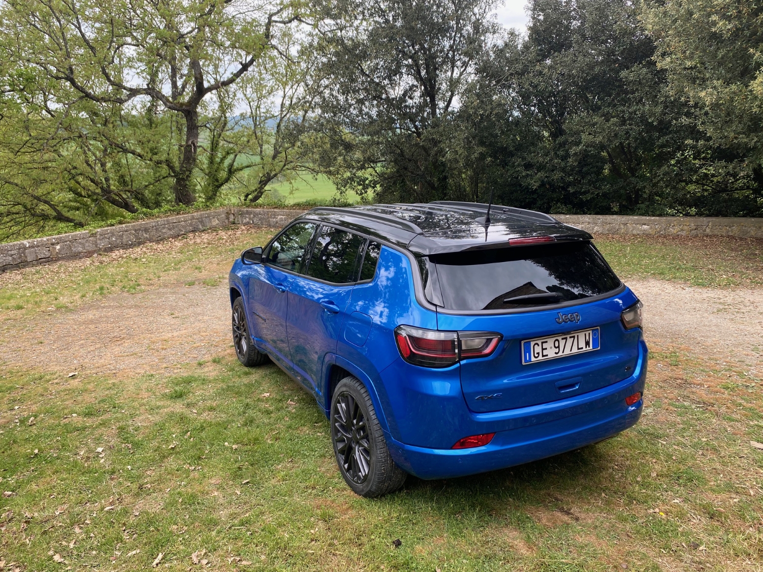 Jeep Compass 4xe híbrido plug-in azul de traseira do alto na grama na Toscana