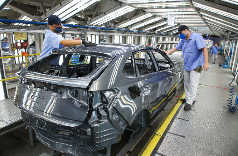 Trabalhadores finalizando a carroceria de um veículo