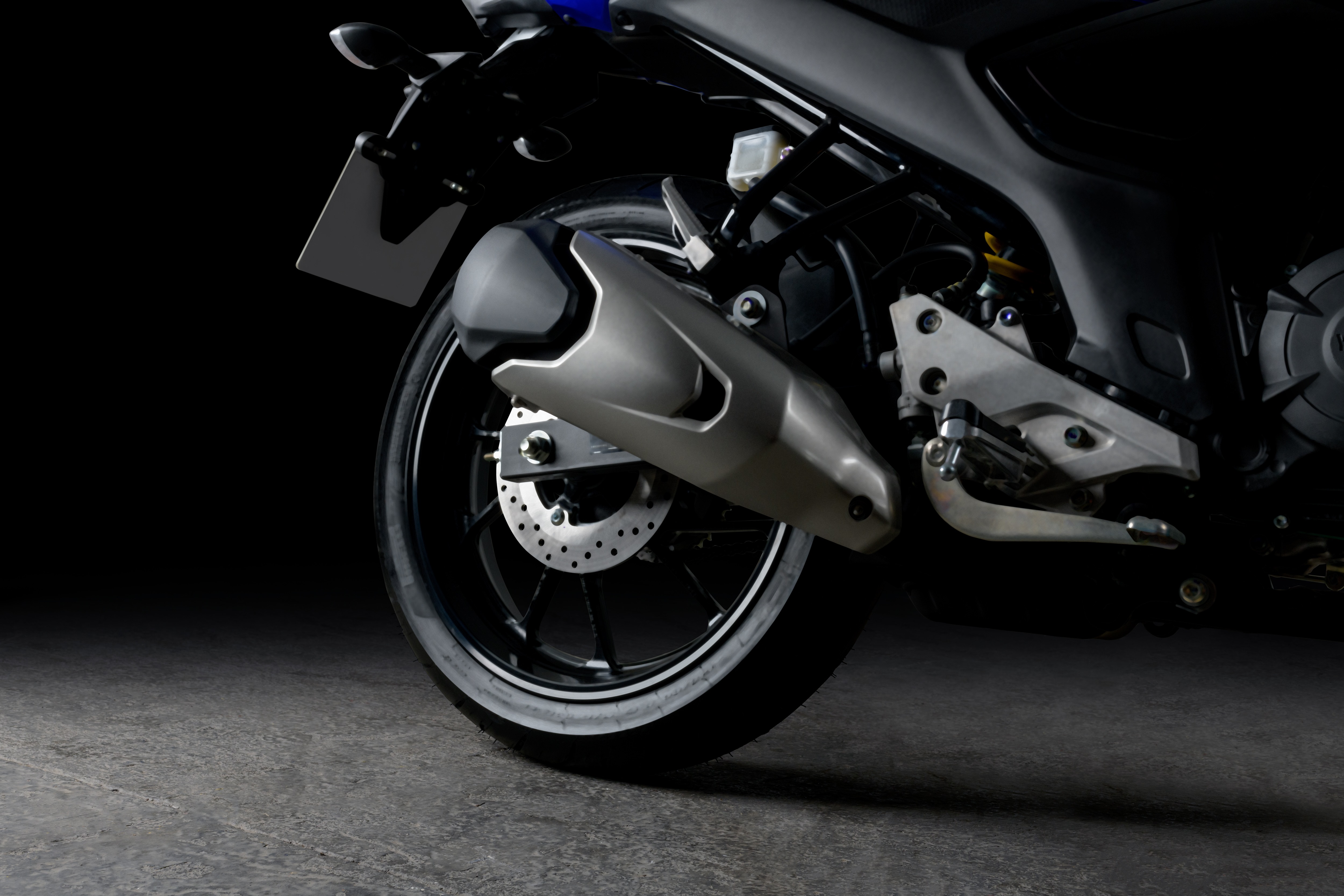 Yamaha Fazer FZ15 azul, detalhe da roda traseira e escapamento.