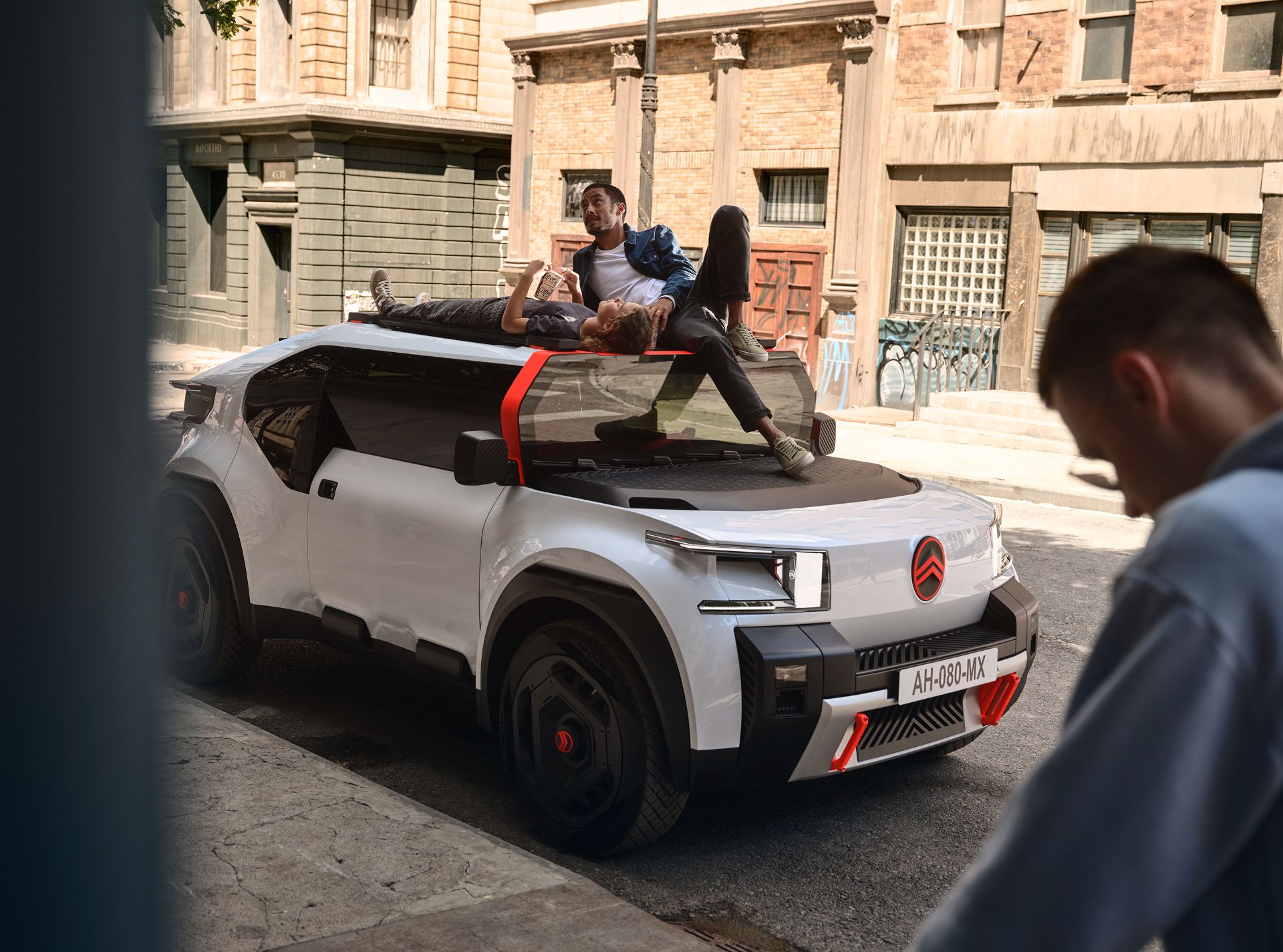 Novo carro conceito da Citroën visto da diagonal frontal. Há uma pessoa em cima do teto, apoiando-se na lacuna abaixo do para-brisa dianteiro.