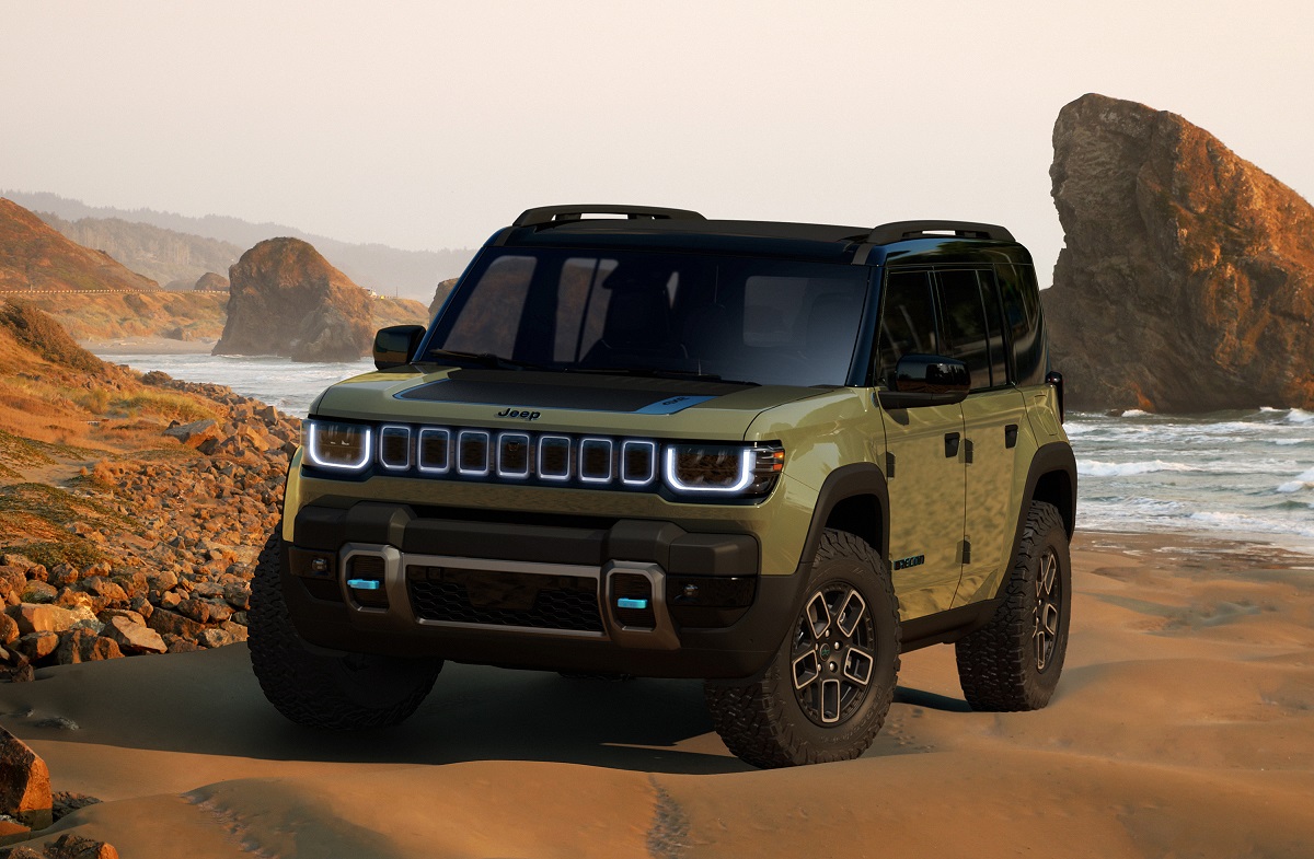 Jeep Recon em tom verde visto da diagonal frontal em uma praia. 