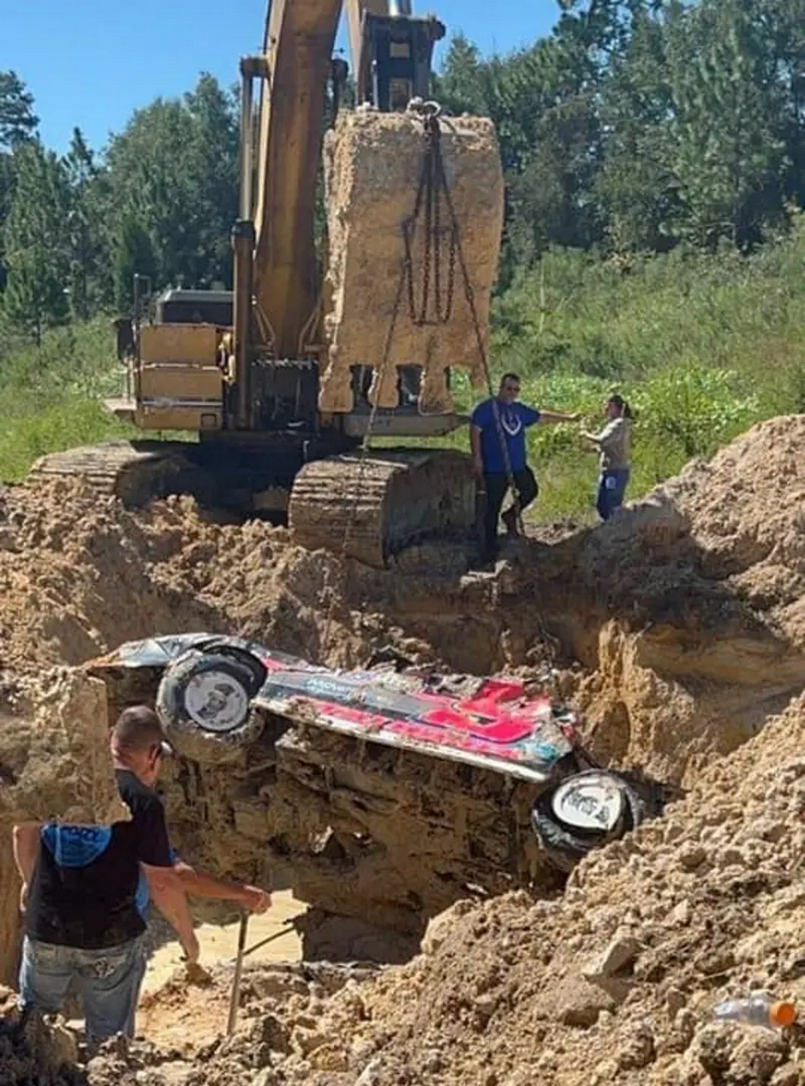 Carro de corrida sendo retirado por trator do buraco de areia.