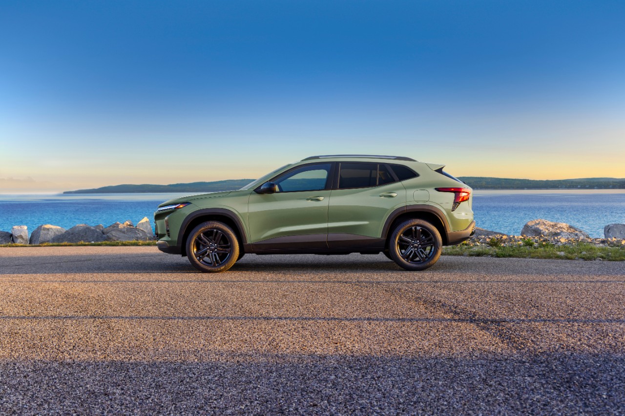 Visão lateral do SUV Chevrolet Trax Activ na cor Verde Cacto. O veículo está estacionado em uma rodovia, de frente para um lago. Modelo de pré-produção. 