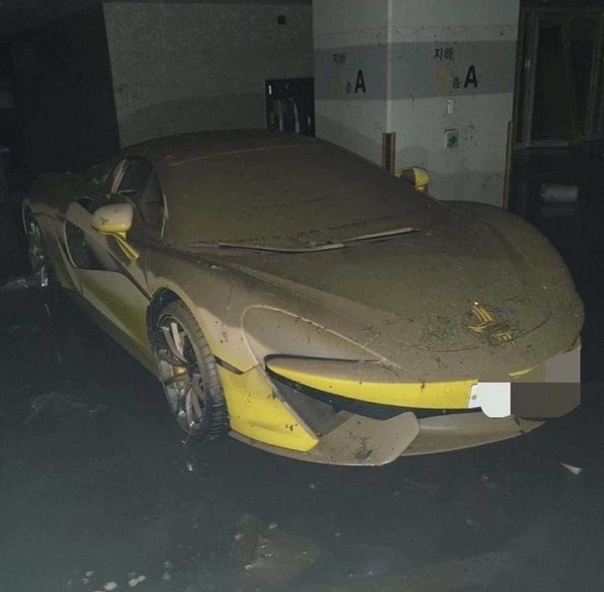 McLaren amarelo coberto de lama em garagem. 
