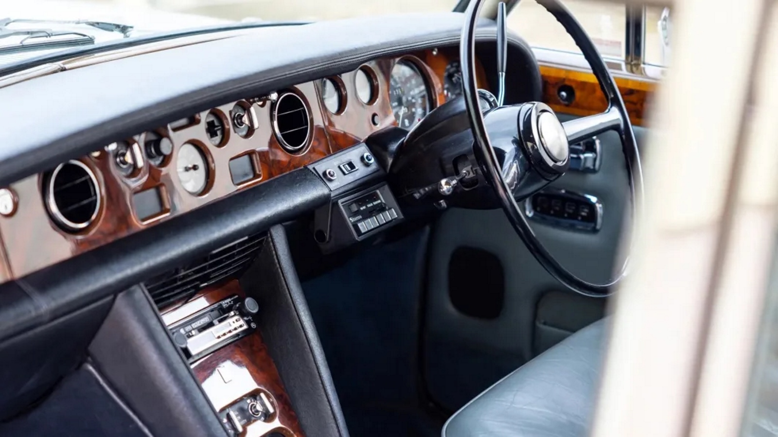 Interior do Rolls-Royce de Freddie Mercury com painel em madeira e volante. 