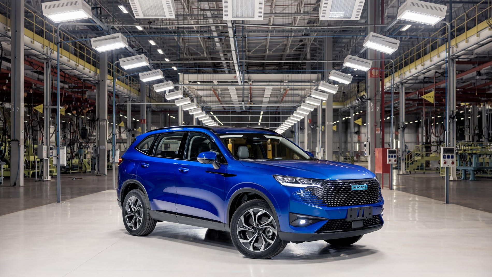 Haval H6 versão brasileira na cor azul visto da diagonal frontal em fábrica da GWM; modelo está na lista de lançamento 2023 de SUVs elétricos e híbridos no Brasil.