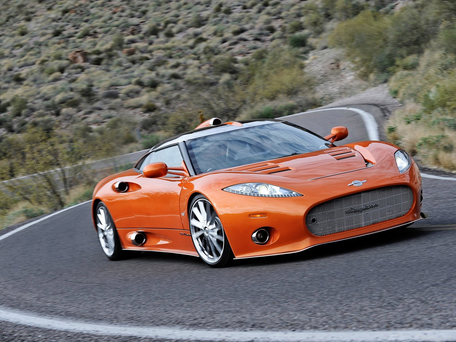 Spyker C8 laranja de frente em movimento em estrada