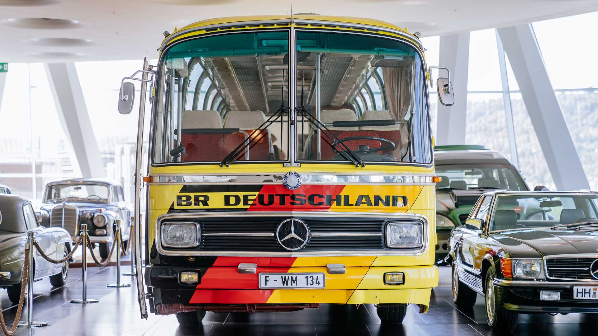 Réplica idêntica de um Ônibus Mercedes personalizado para a seleção da Alemanha na Copa do Mundo de 1974. O veículo é visto frontalmente em um estande de museu.