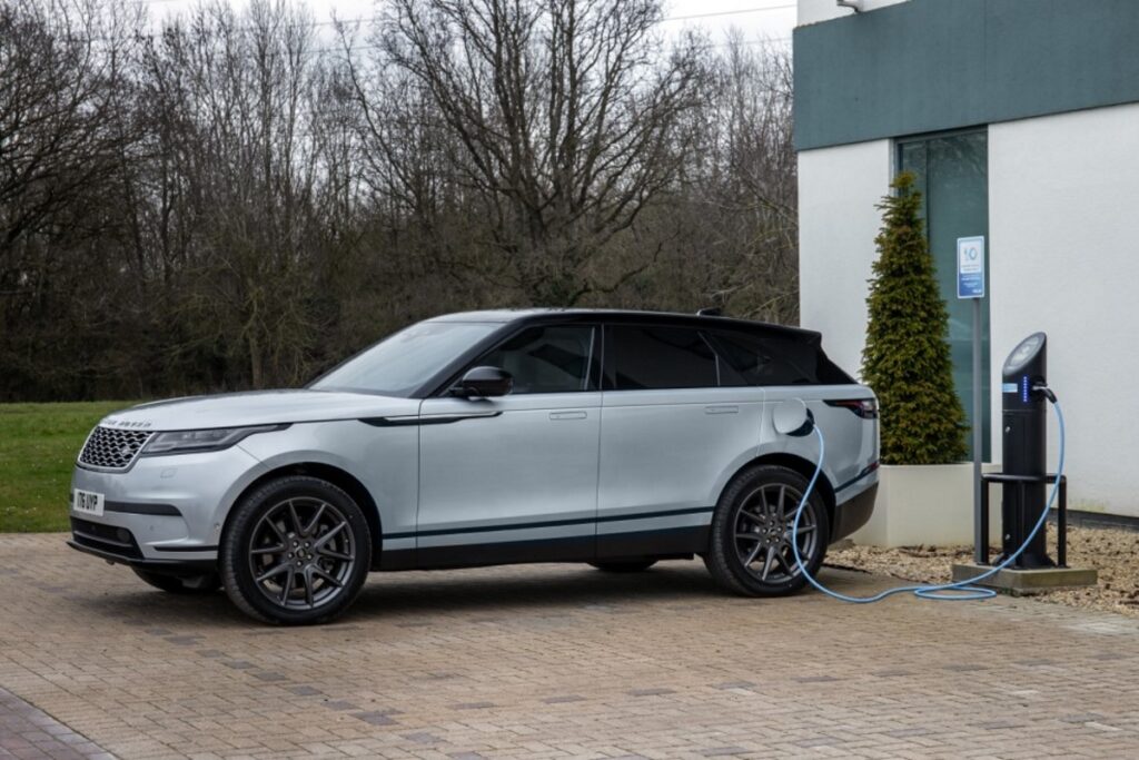 Novo Range Rover Velar 2023 prata visto da diagonal frontal em uma estação de carregamento.