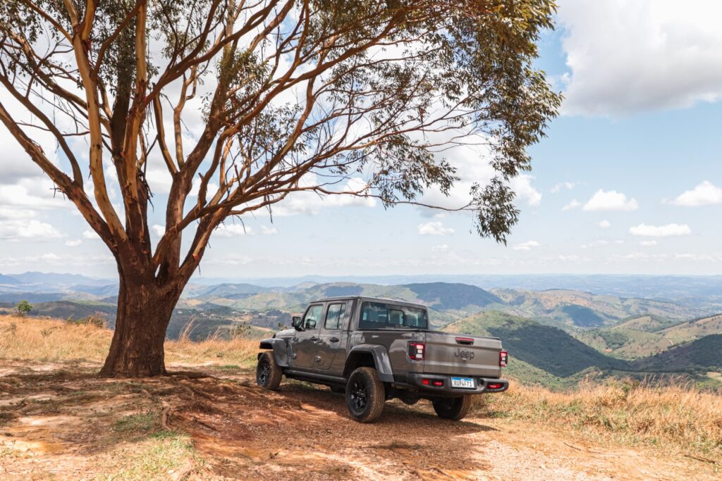 Jeep Gladiator Rubicon 3.6 V6 modelo 2022 cinza de traseira na paisagem ao lado da árvore estático