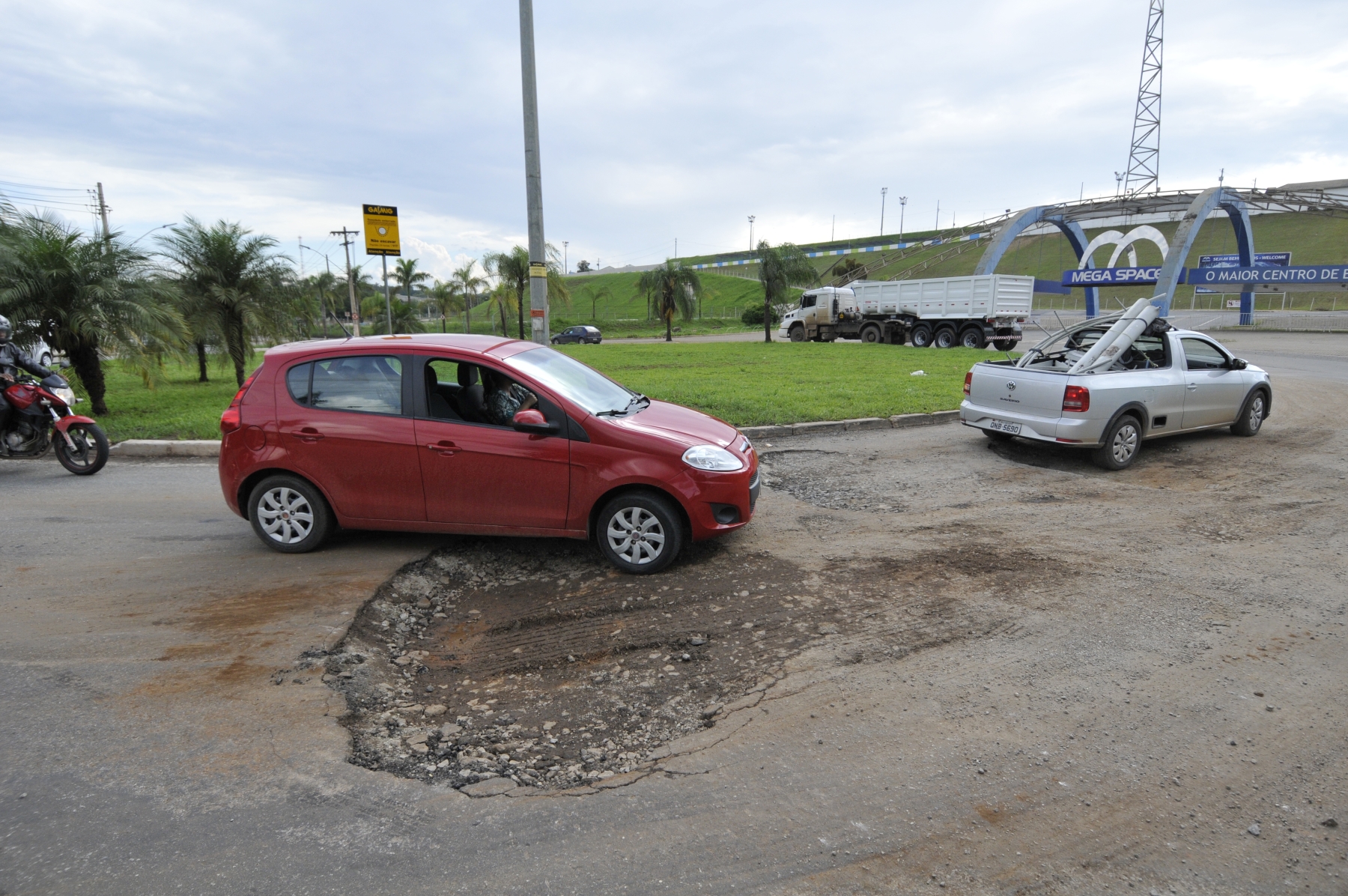 Buracos nas pistas em frente Mega Space Santa Luzia carros e moto passando prejuízo rodas pneus