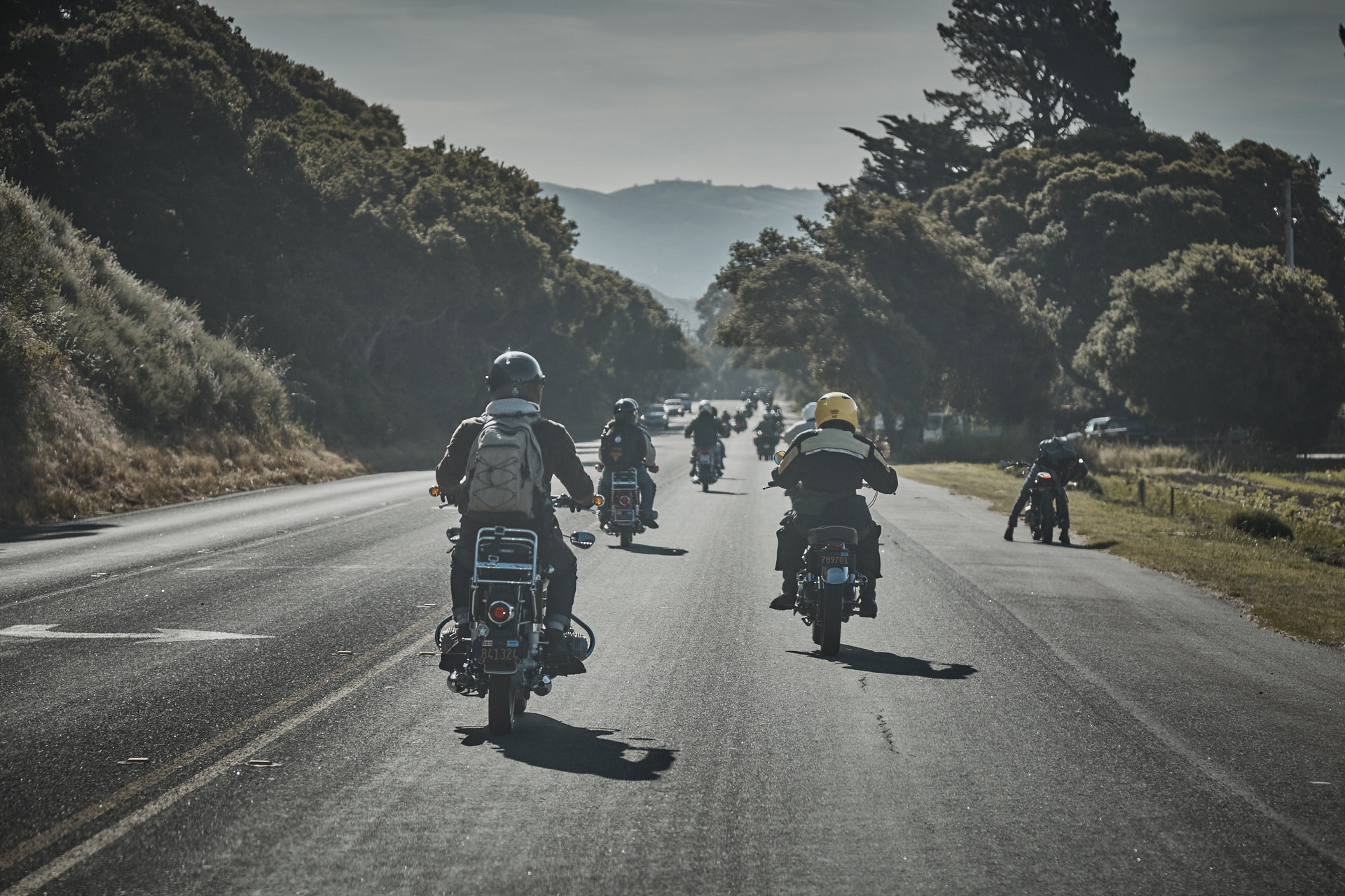 Encontro de motos sendo realizado na estrada. Na foro, é possível ver a passagem, na via, de várias motocicletas juntas.