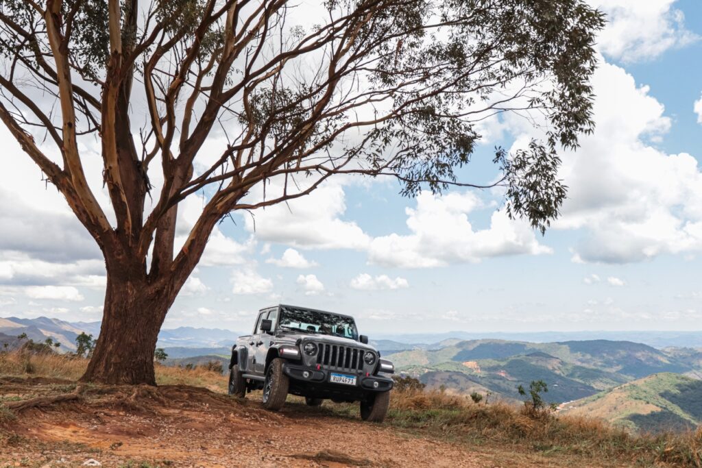 Jeep Gladiator Rubicon 3.6 V6 modelo 2022 cinza de frente na paisagem do lado da árvore estático