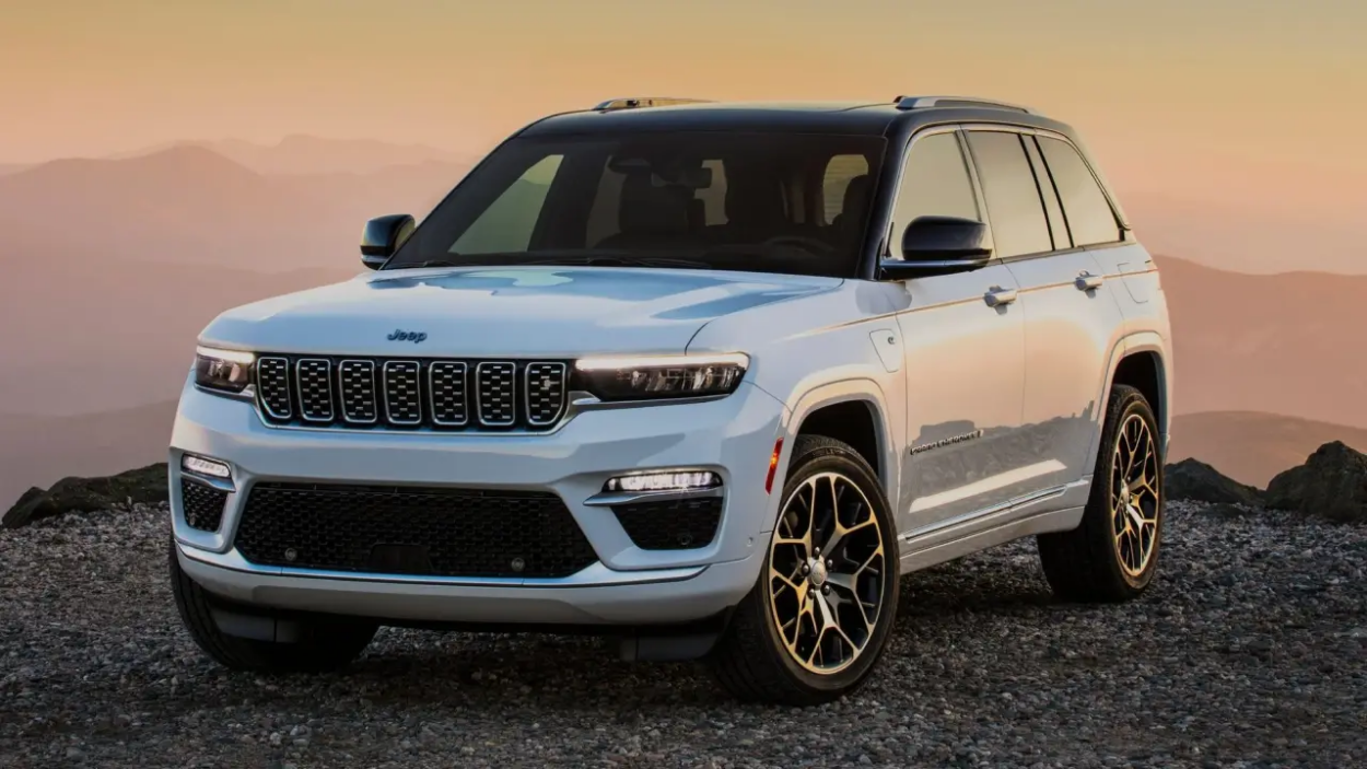 Jeep Grand Cherokee 4xe branco visto da diagonal frontal parado sobre penhasco. 