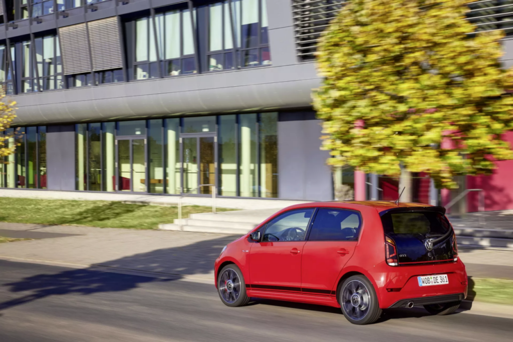 Volkswagen Up! GTI visto da diagonal frontal estacionado na rua. Há uma grande casa ao seu lado.