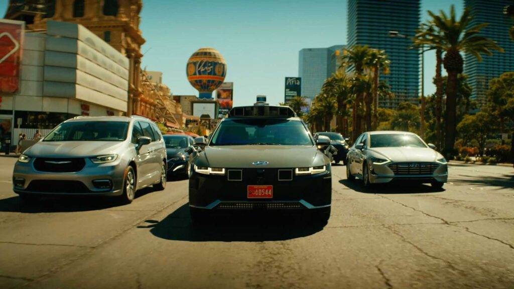 Ioniq 5 Robotaxi andando em rua de Las Vegas. Há outros veículos ao lado dele.