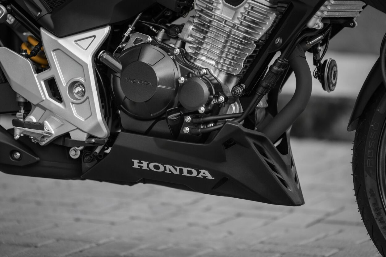 Honda CB 300F Twister modelo 2023 amarela detalhe do motor estática no calçamento