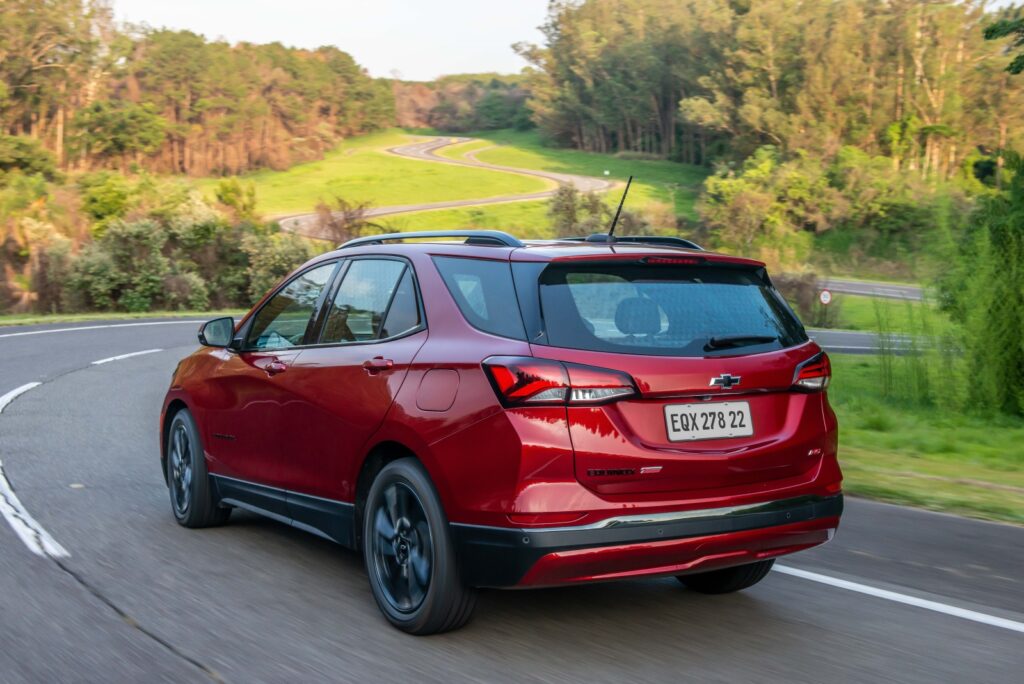 Equinox RS vermelho visto da diagonal traseira em movimento na estrada; para matéria sobre versões especiais da Chevrolet.