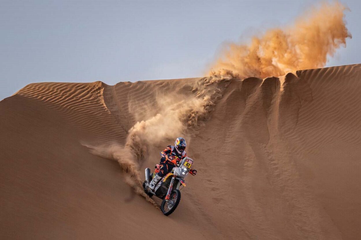 Rally Dakar 2023 KTM 450 Rally Factoring amarelo vermelho de frente descendo nas dunas deserto em movimento piloto argentino Kevin Benavides