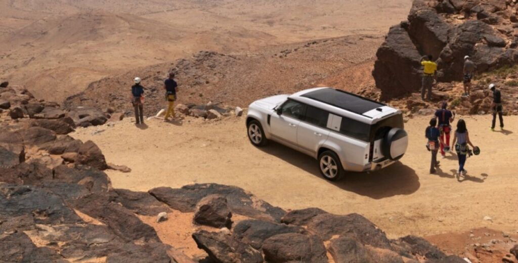 Land Rover Defender 130 visto panoramicamente da diagonal frontal em meio a um penhasco de terra.