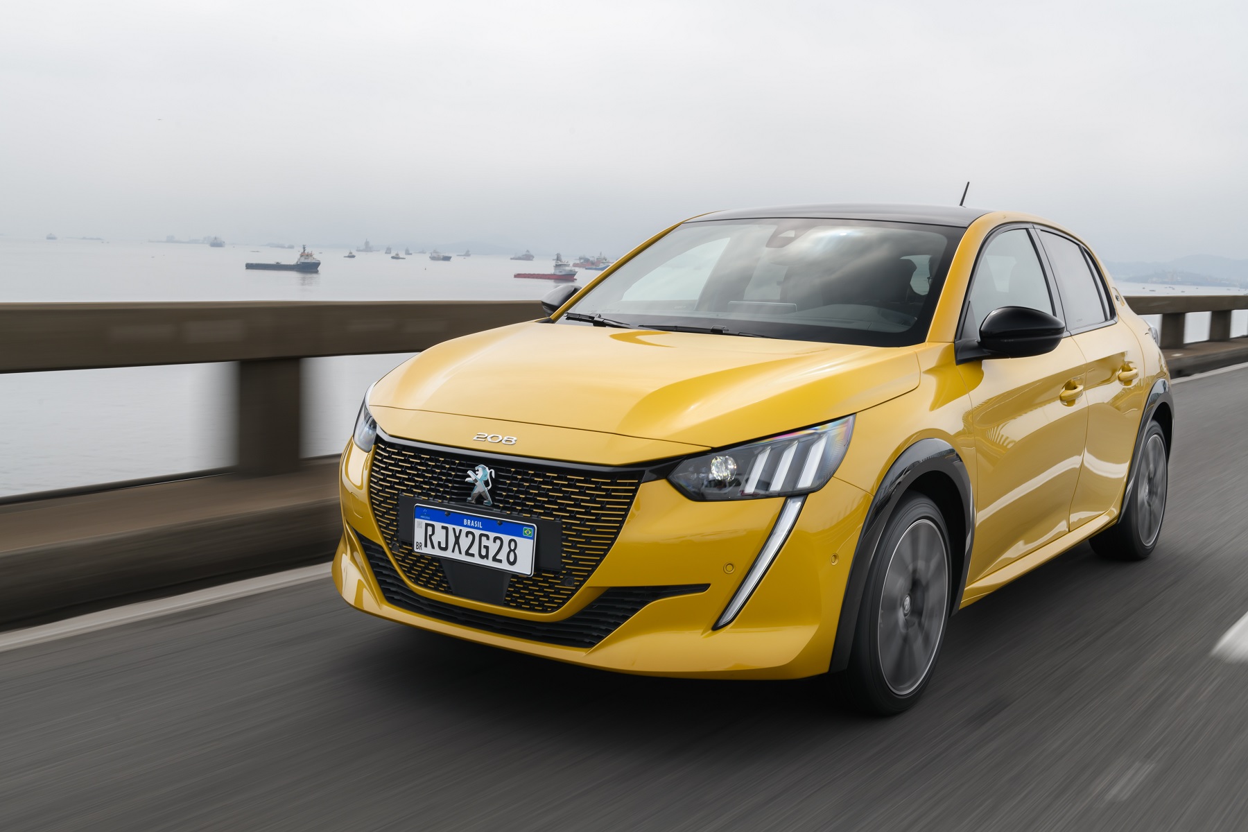 Peugeot e208 GT amarelo de frente em movimento