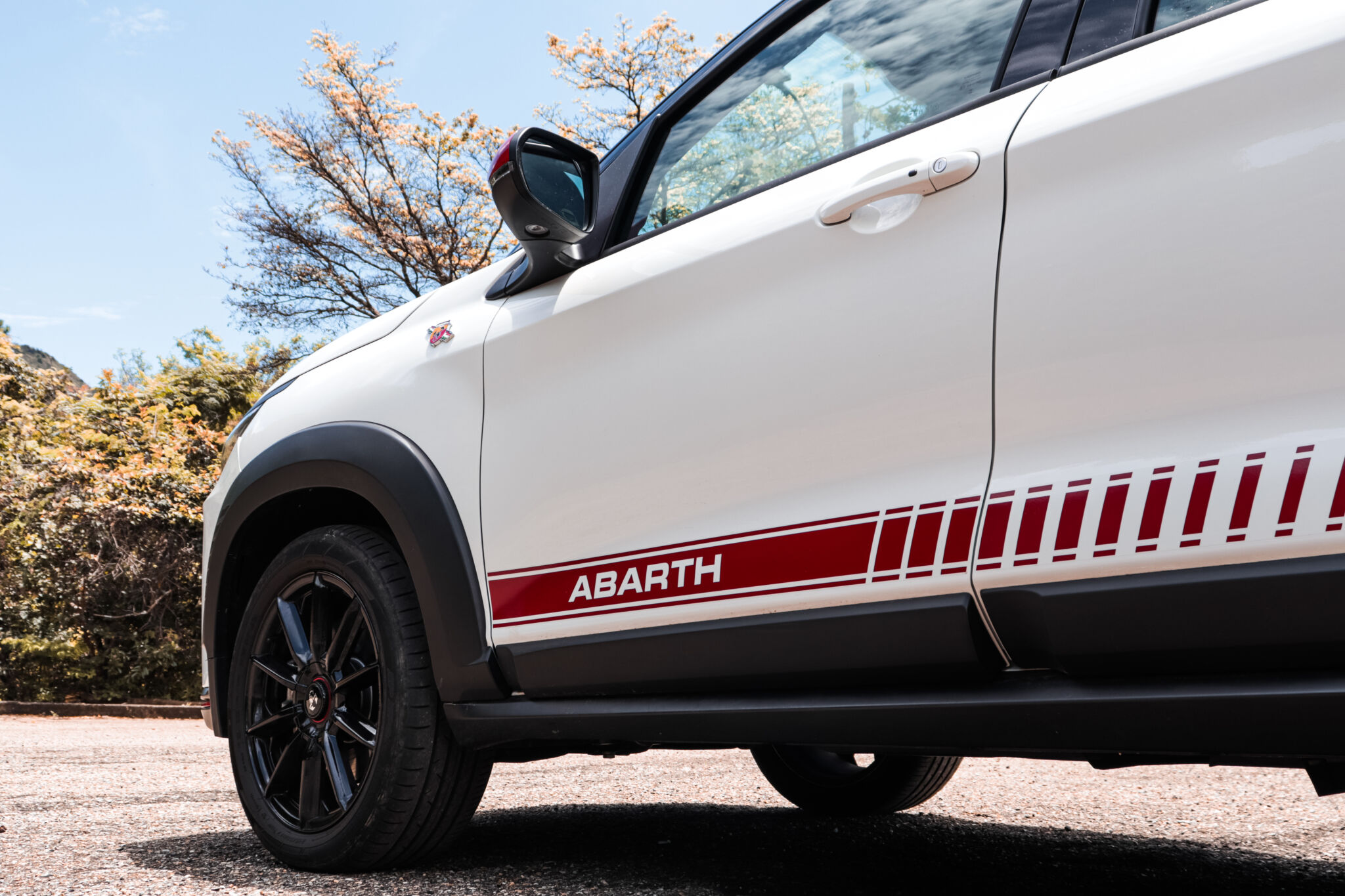 Detalhes da base da porta dianteira do Pulse Abarth destacando a faixa vermelha com o nome da divisão em branco e as rodas de liga leve de 17 polegadas, raiadas, em preto com o escorpião na calota central