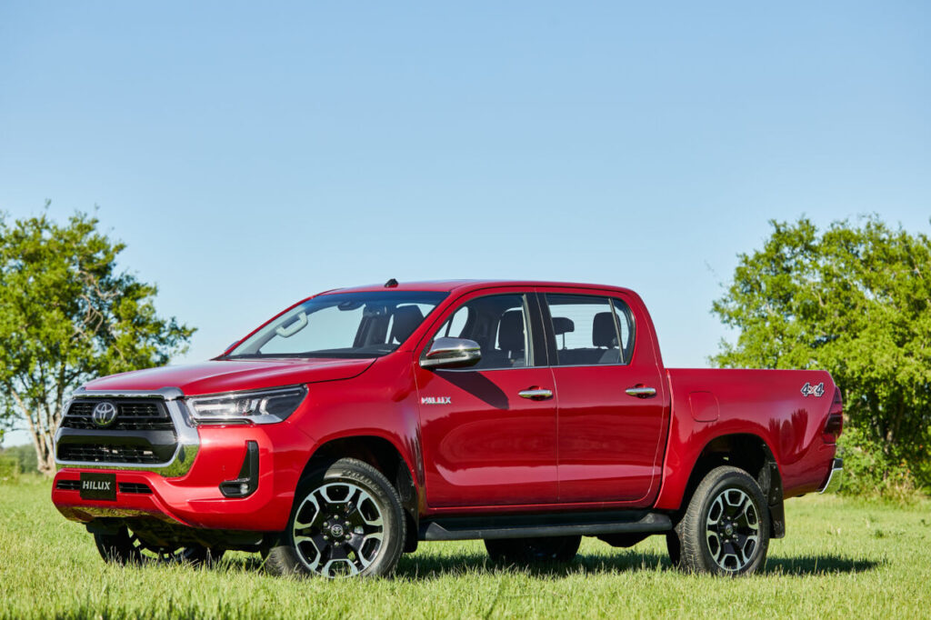 Toyota Hilux 2022 vermelha visto da lateral na grama.