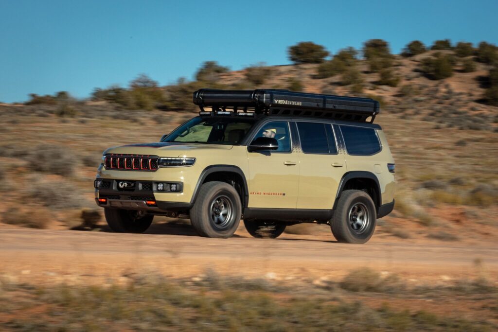 Jeep Grand Wagoneer Overland visto da diagonal frontal em meio a terreno desértico.