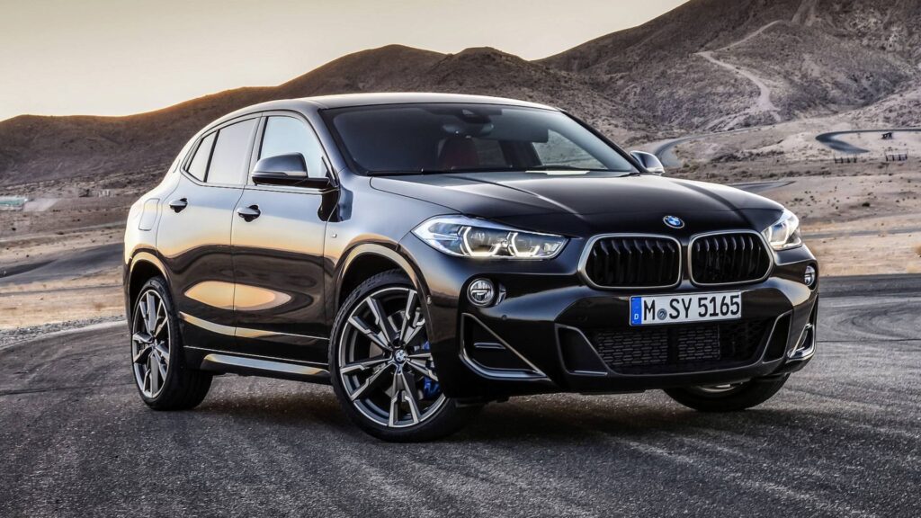 BMW X2 preta vista da diagonal frontal em chão de terra.