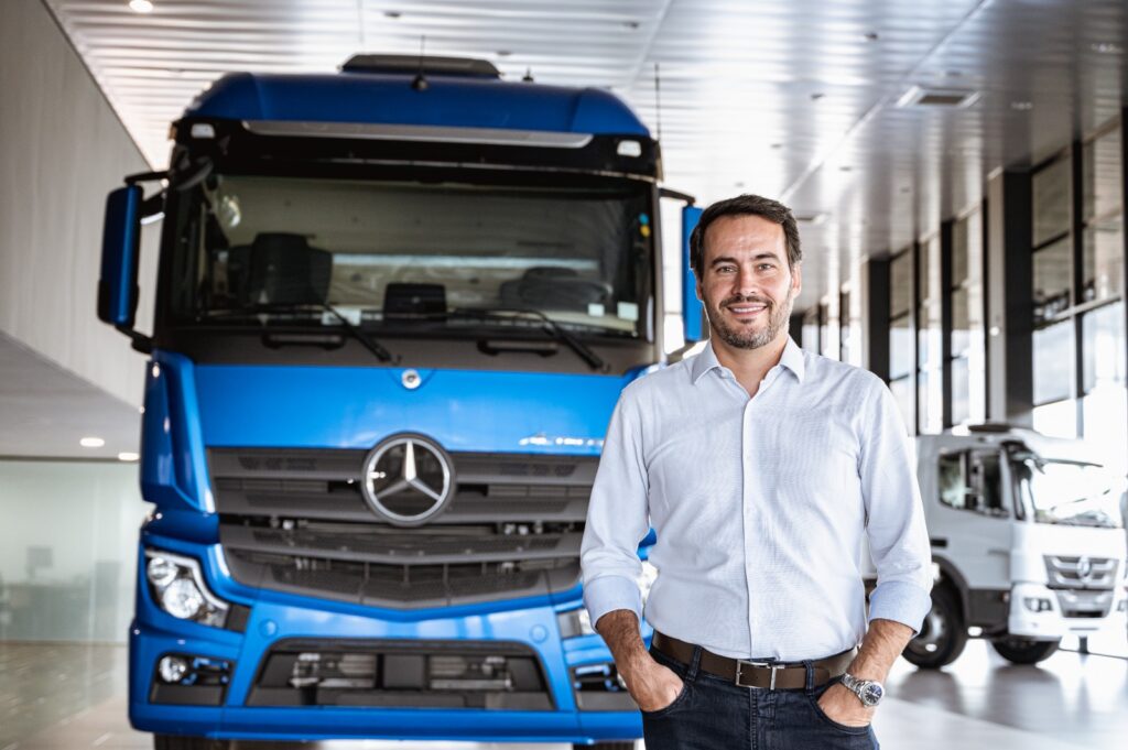 CEO da empresa em frente a um caminhão da Mercedes. 