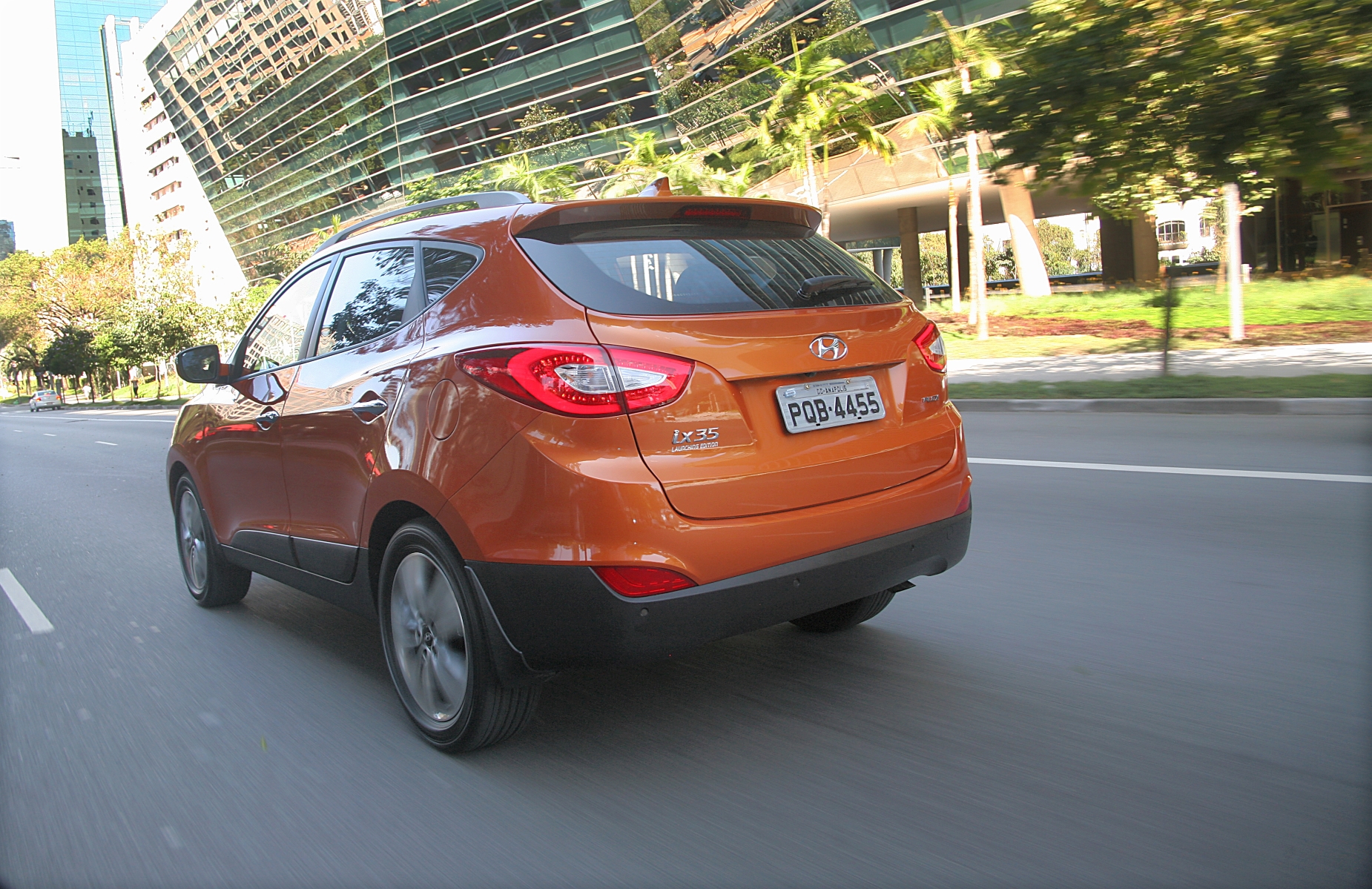 hyundai ix35 modelo 2015 laranja de traseira em movimento no asfalto