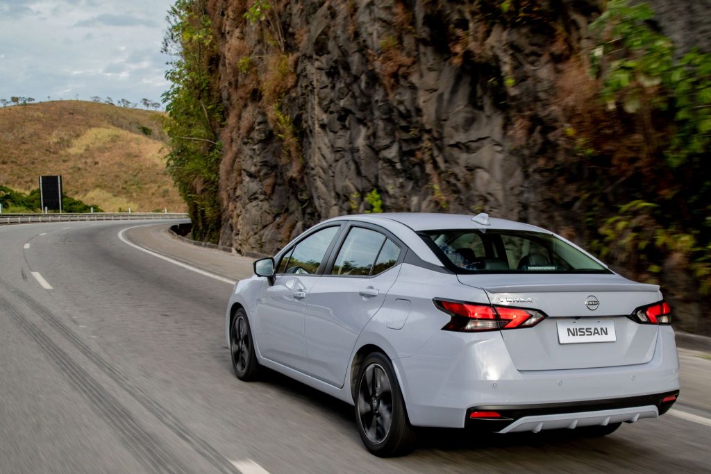 Nissan Versa 2024 de traseira em movimento, sedã foi reestilizado.