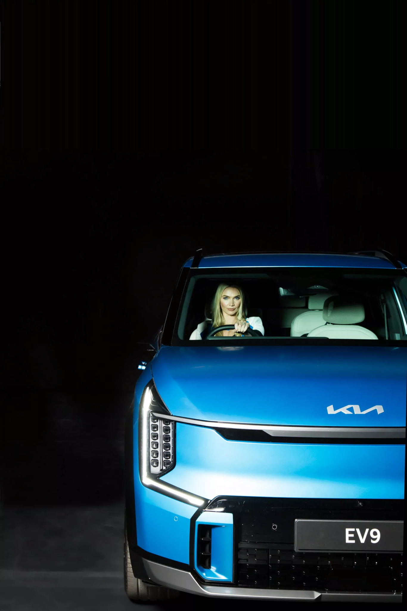 Kia EV9 azul, carro elétrico da marca, com a modelo Jodie Kidd no interior