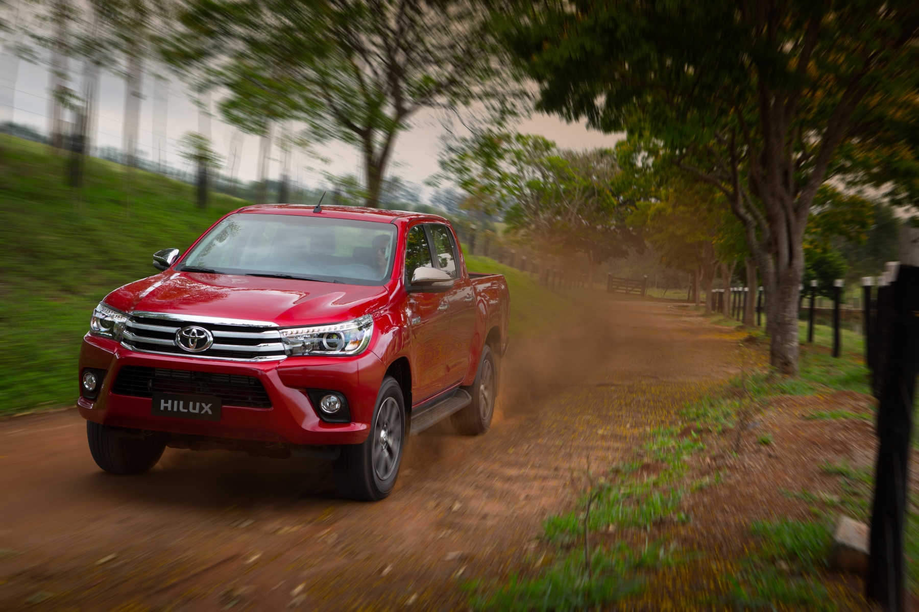 toyota hilux modelo 2015 vermelha de frente em movimento na estrada de terra