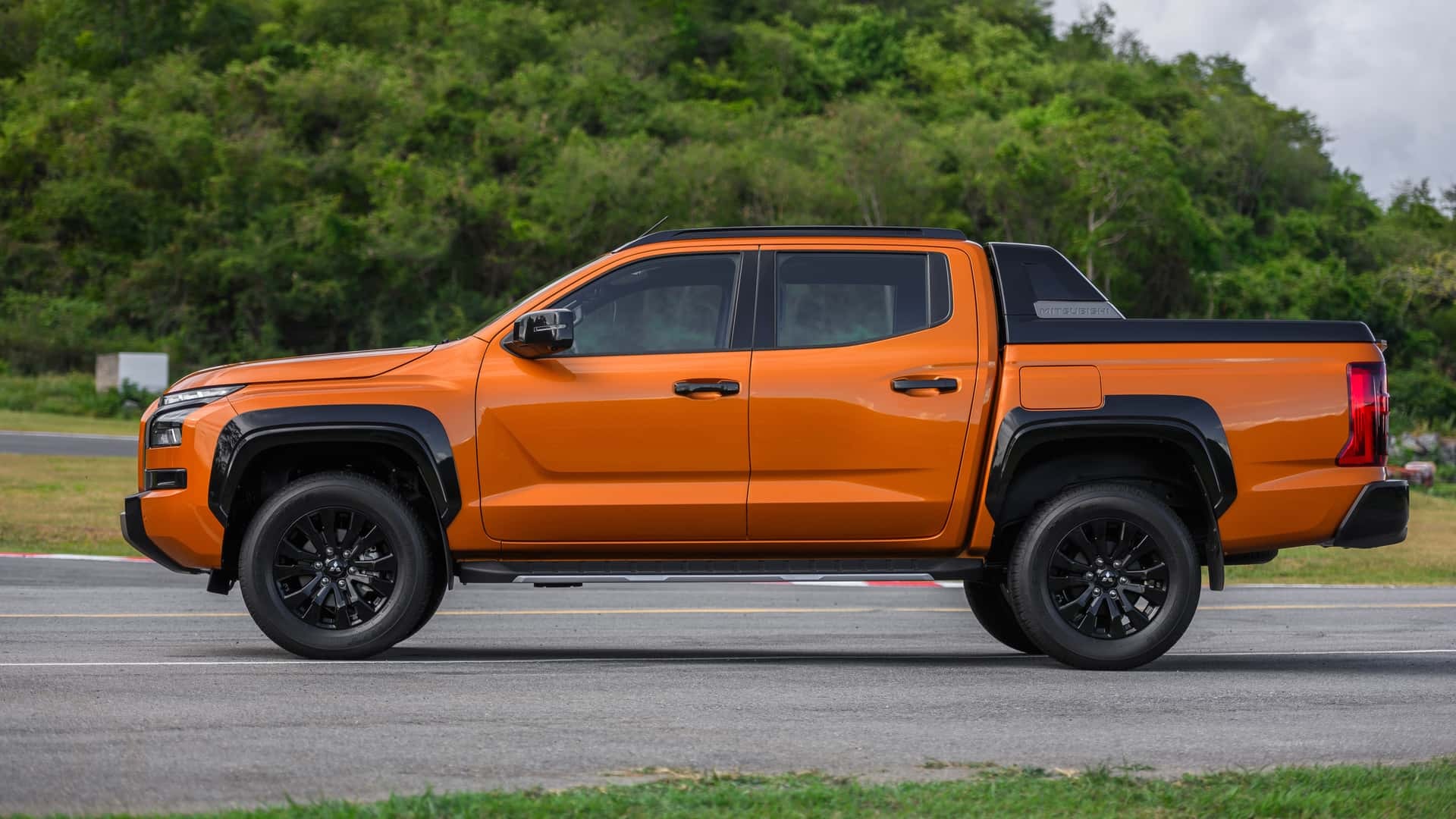 Nova Mitsubishi L200 2024 laranja de lateral estacionada