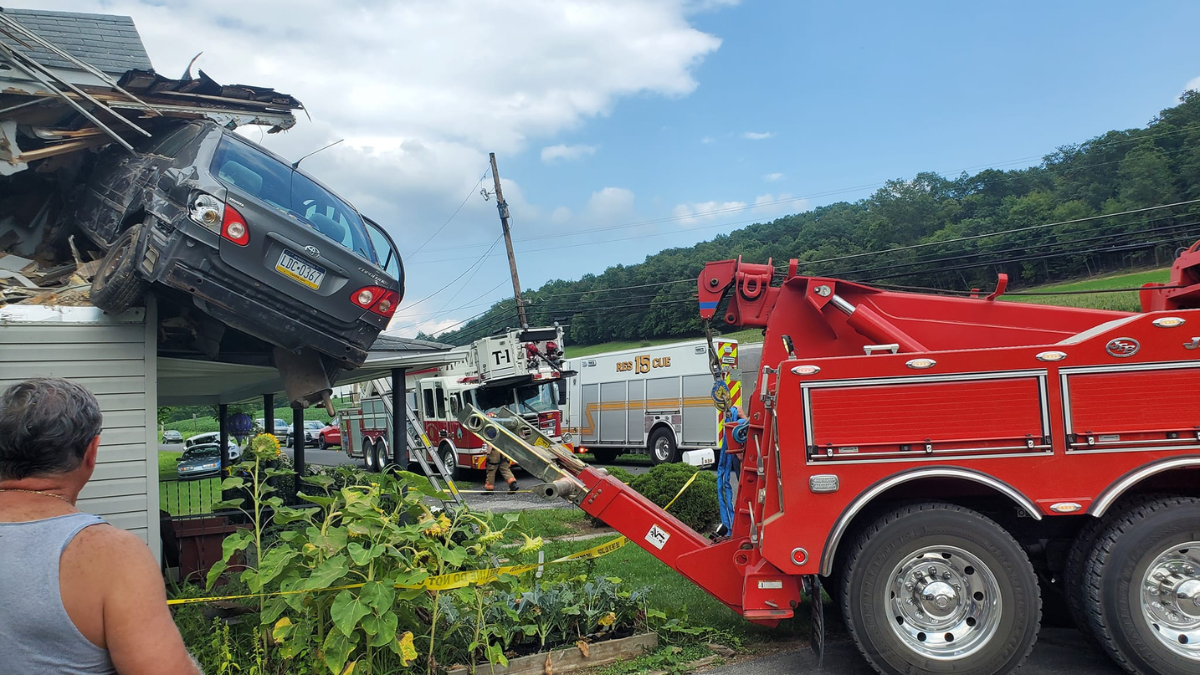 Toyota Corolla jogado por motorista em segundo andar de casa sendo retirado por guindaste